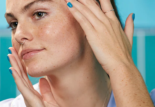 Woman applying serum on her face with hands